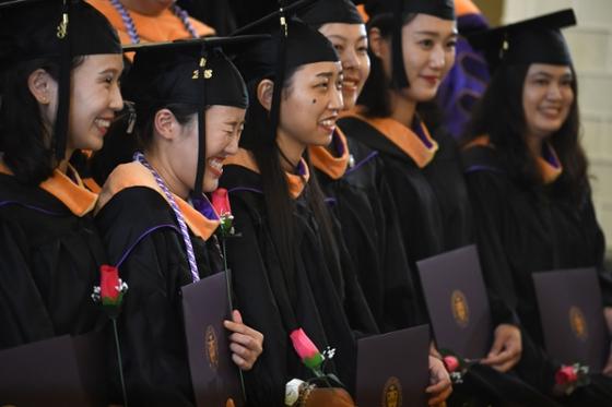 图为一群戴着帽子穿着长袍的国际学生, 在波胆网站毕业典礼上
