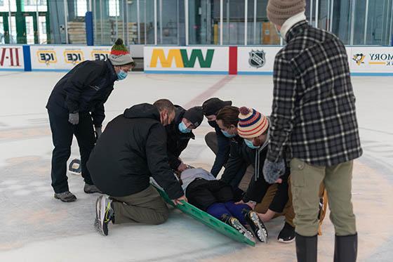 MSAT学生戴着口罩在溜冰场的照片, 帮助一个躺在冰上受伤的冰球运动员