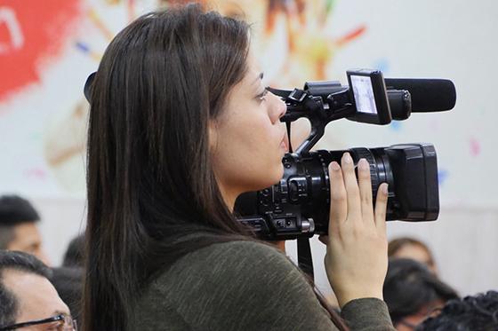 图为一名妇女望着肩头上摄像机的取景器. 
