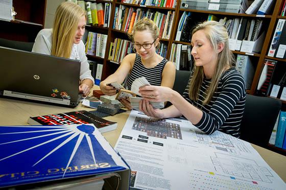 图为三名波胆网站的学生在图书馆的桌子旁工作