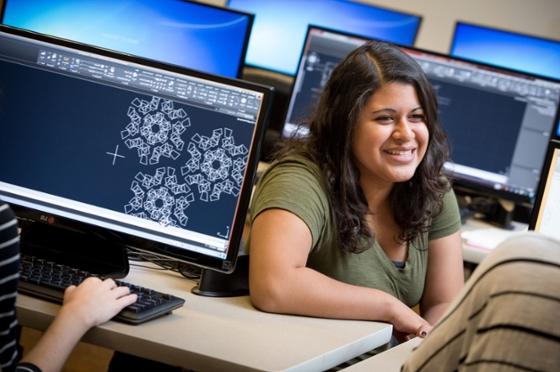 图为一名波胆网站的学生坐在实验室的电脑前微笑. 