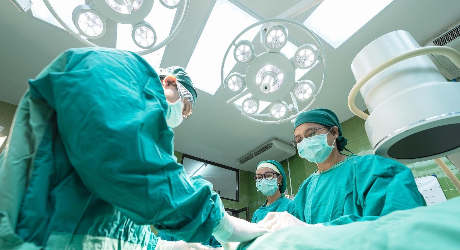 上面的照片显示，外科医生俯身在手术台上进行手术