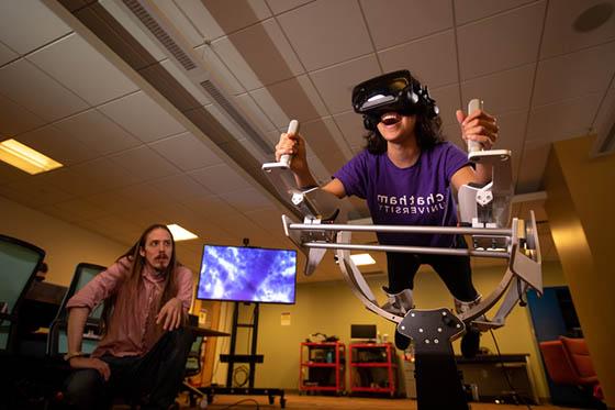图为身穿波胆网站紫色校服的学生, in a virtual reality machine, while a professor watches on