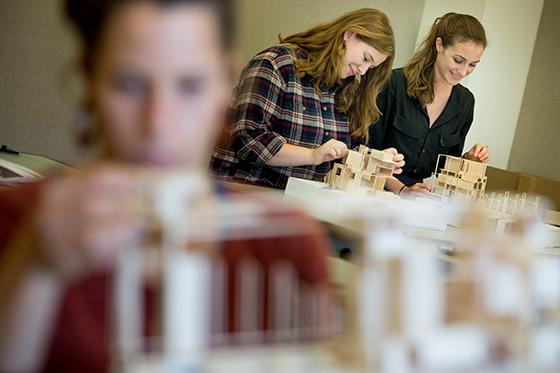 图为两名波胆网站的学生在建筑实验室用木头建造模型.
