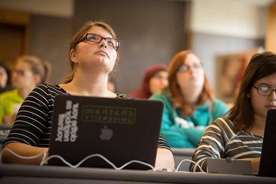 图为一名英国波胆网站的学生在演讲厅里专心听讲, 她面前放着一台贴着波胆网站标签的笔记本电脑