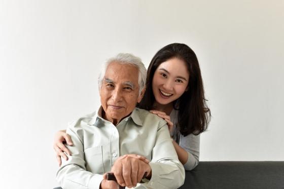 一个年轻女子和一个老人微笑着合影的照片