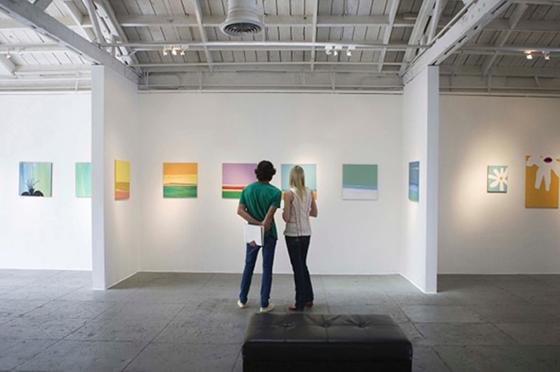 两个年轻人站在一个艺术展上，看着白色墙壁上五颜六色的画. 