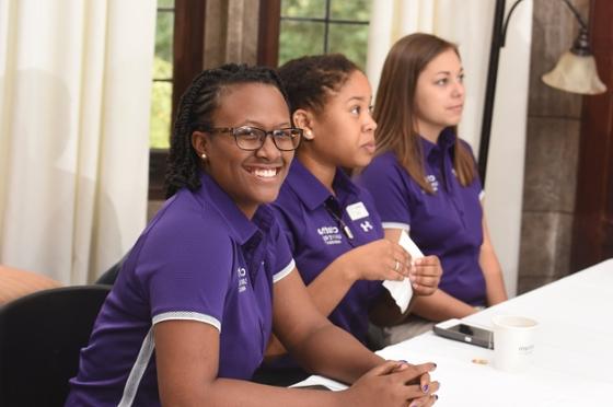 图为三名波胆网站的女学生穿着相配的紫色衬衫, 准备登记参加活动的人