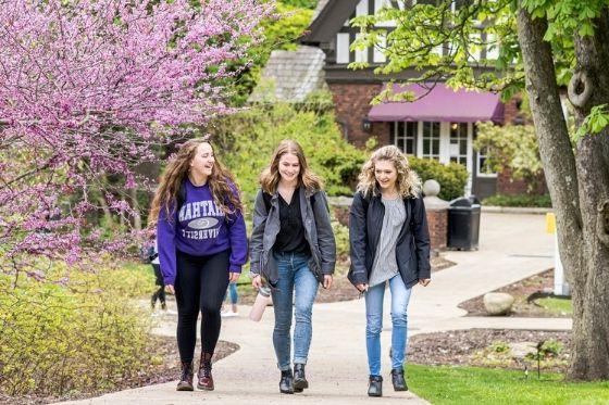 Photo of three Chatham University students walking outside on Shadyside Campus